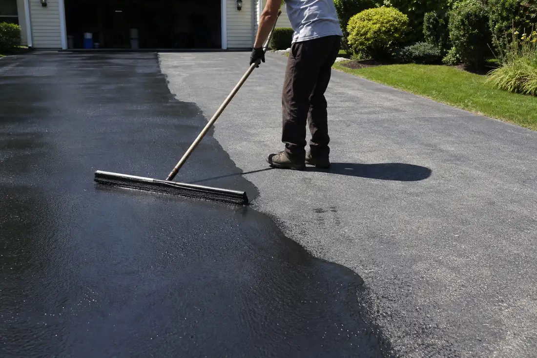 Sealcoating being applied by squeegee to a residential driveway